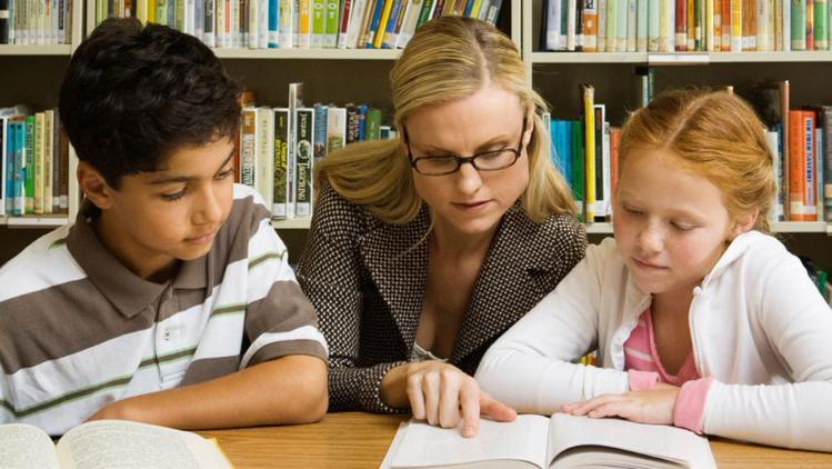 Woman and 2 children reading a book in a library
