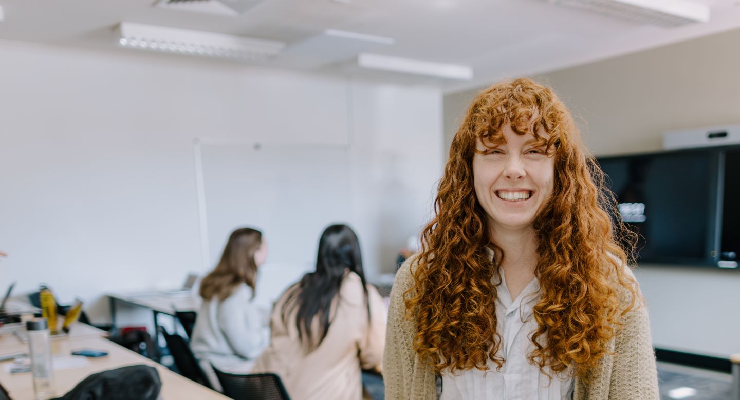 Female student sitting on a desk in class room on campus