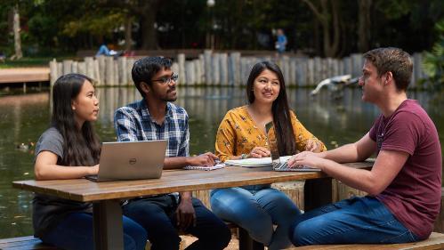 Student group sitting at table near duckpond