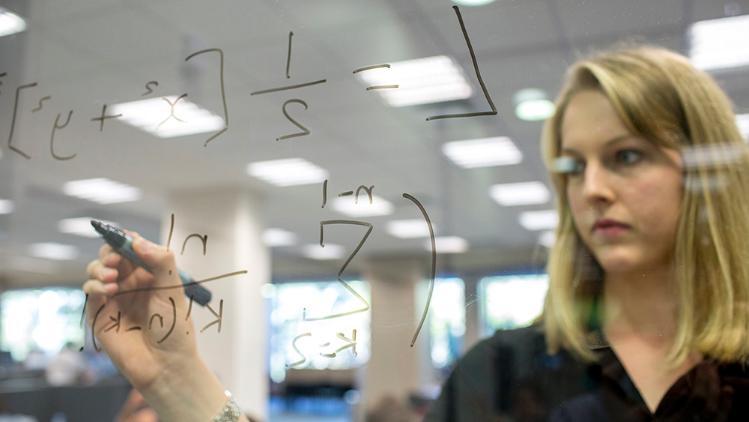 Female student studying/writing algebra on a translucent white board