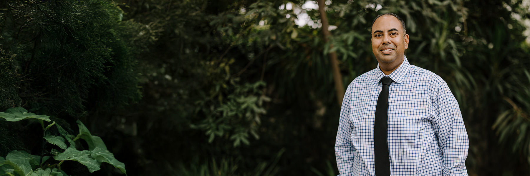 Dinesh Dodhy with a backdrop of lush green trees on campus