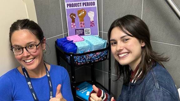 Two young ladies sitting by sanitary products