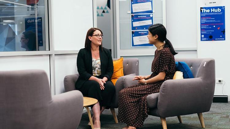 Two people sitting on chairs having a chat