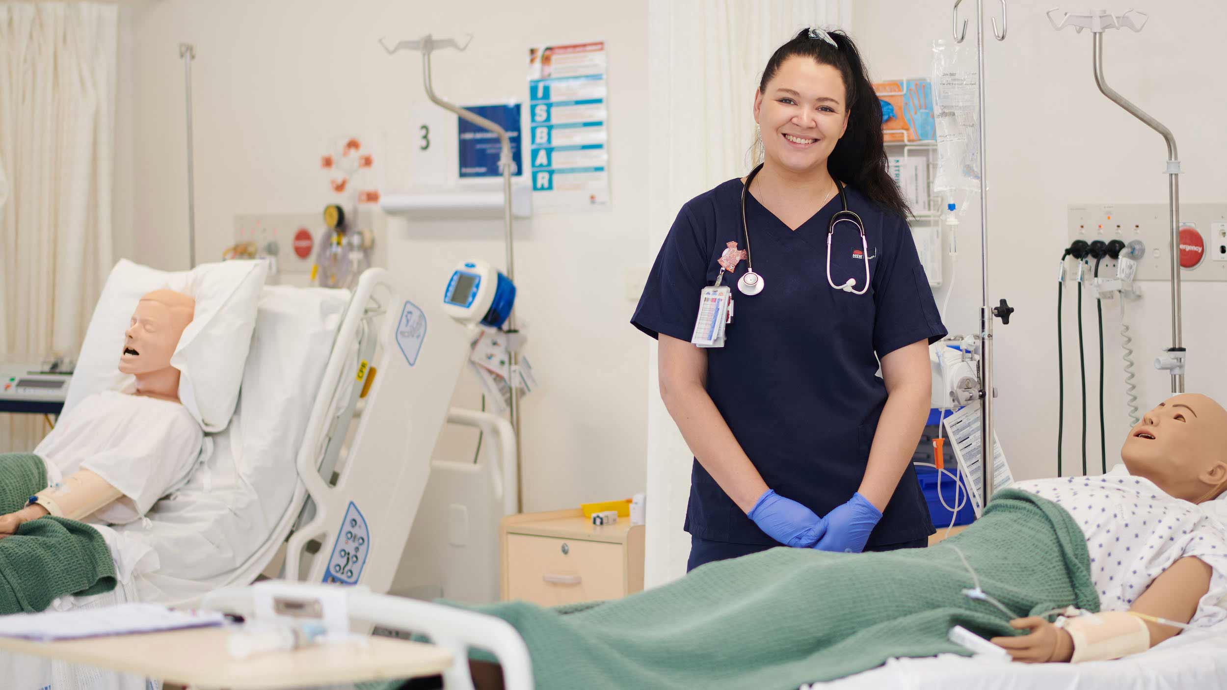 Female nursing students standing in nursing lab with two dummy patients in beds
