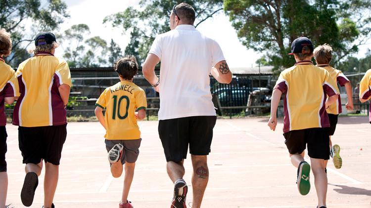 Primary school students run with their physical education teacher