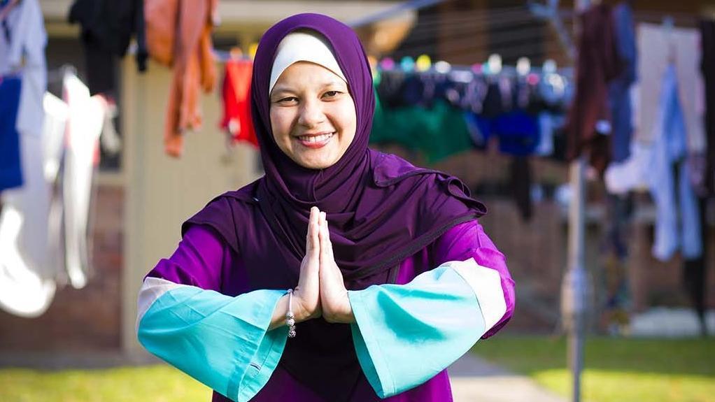 International student stands on teh lawn of a UOW accomodation site. You can see a Hills Hoist in teh background