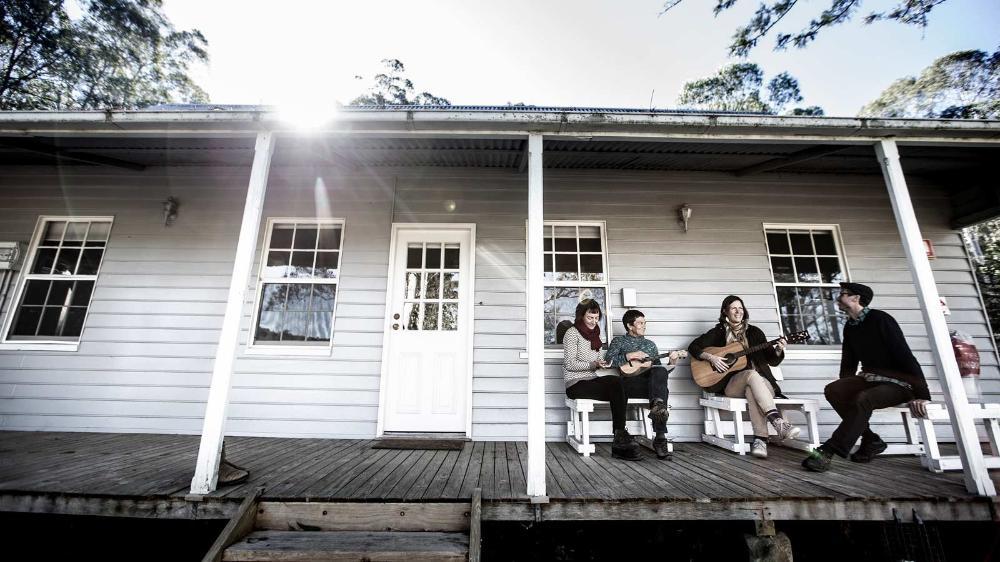 Dr Sarah Hamylton, Dr Leah Gibbs, Dr Lucas Ihlein, and Ms Kim Williams making music together on a veranda.