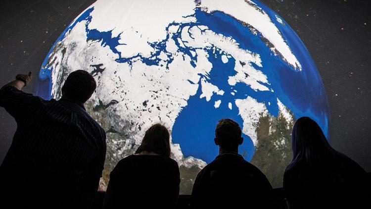 People standing in front of globe on screen