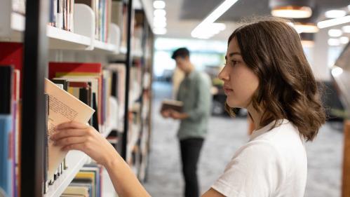SOLA student selecting a book in the library