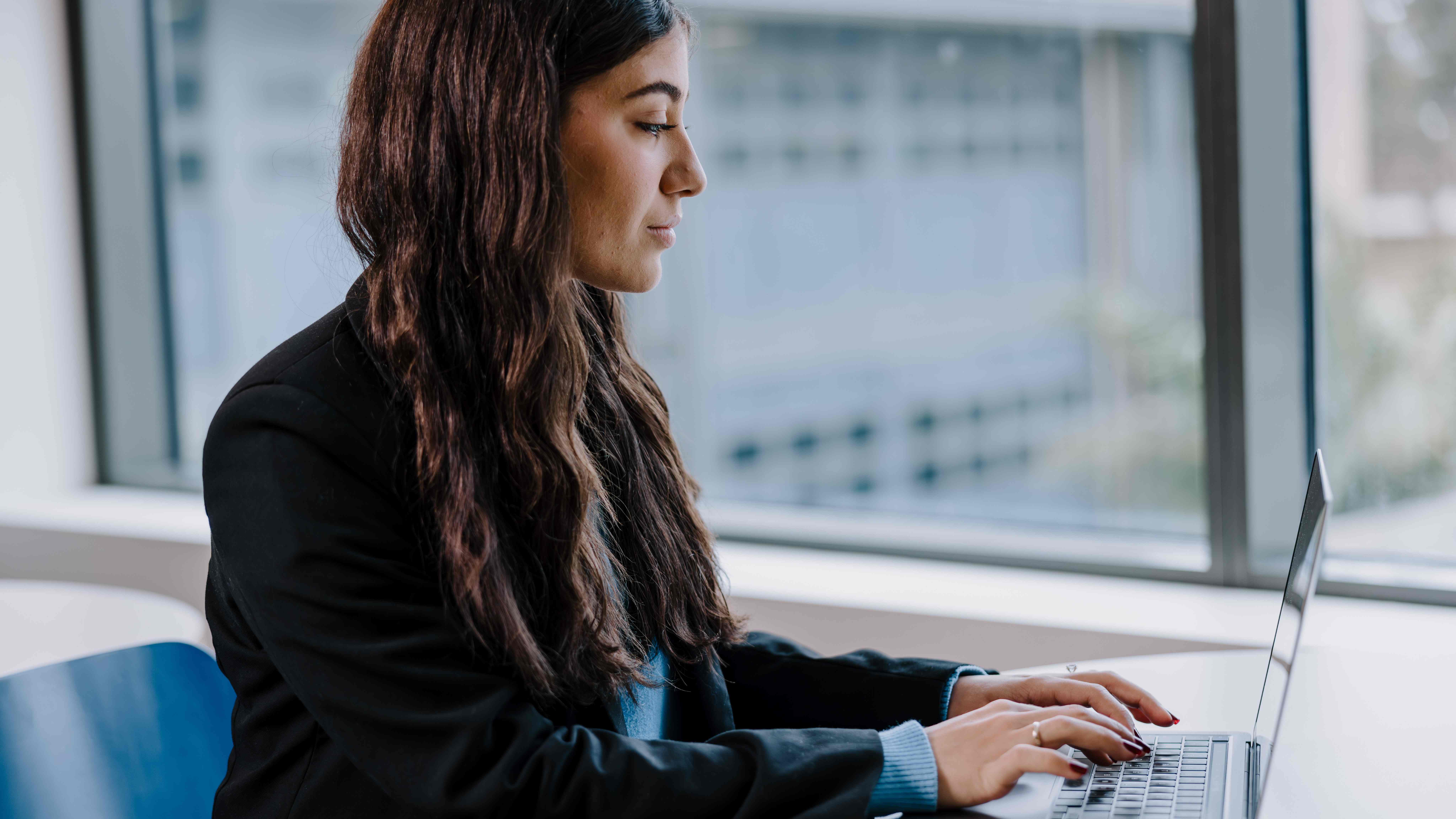 A student sits at a desk using their laptop