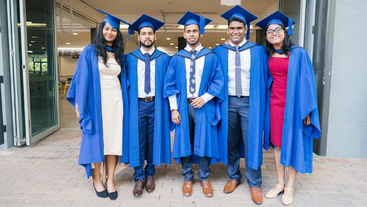 5 graduates wearing academic dress standing in a line