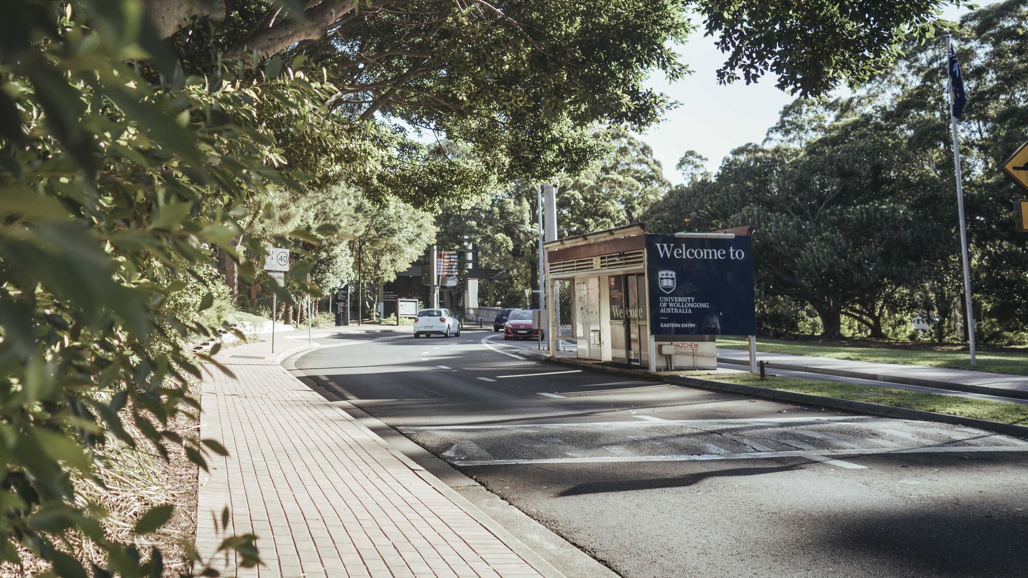 Northfields Avenue entrance to UOW Wollongong campus with roadside parking and campus signage.