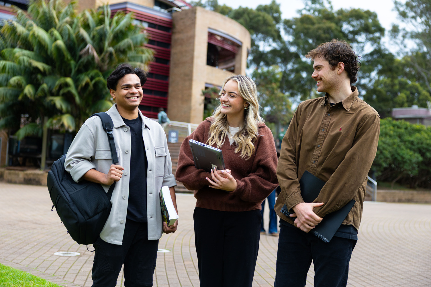 Three students smiling while walking on campus