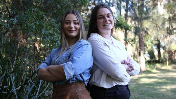 Image of two female students standing back to back