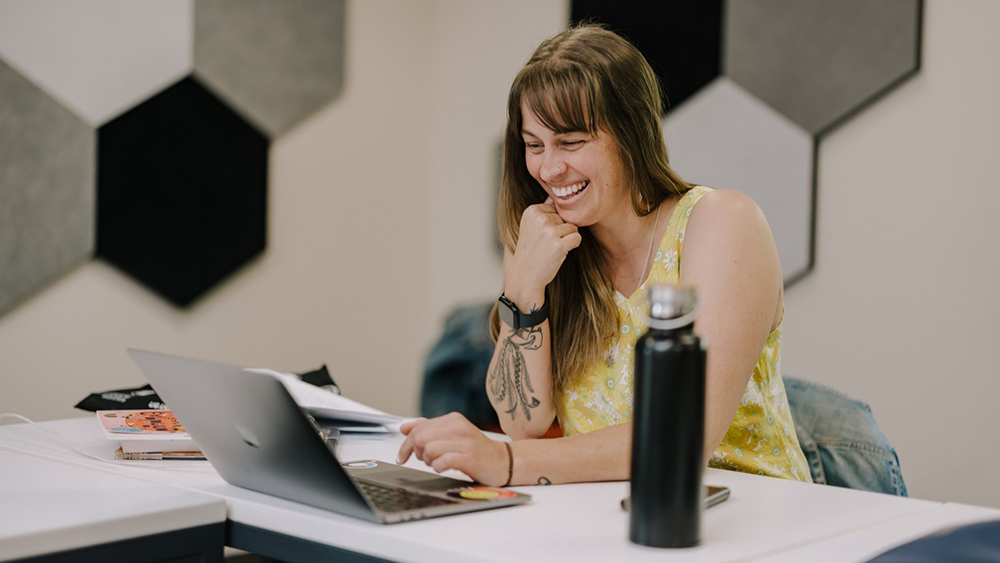 Student sitting at a laptop computer smiling