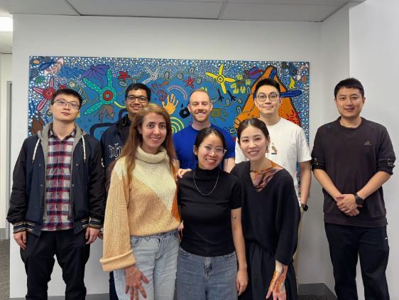 Students smiling in front of a painting