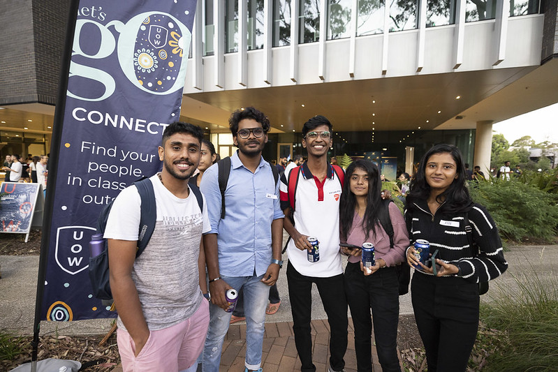 Group of students standing together outdoors at a campus event beside a “Let’s Go Connect” banner.