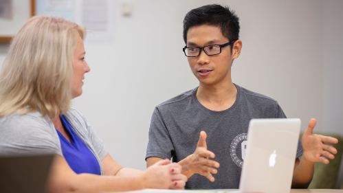 Student and teacher talking at a desk