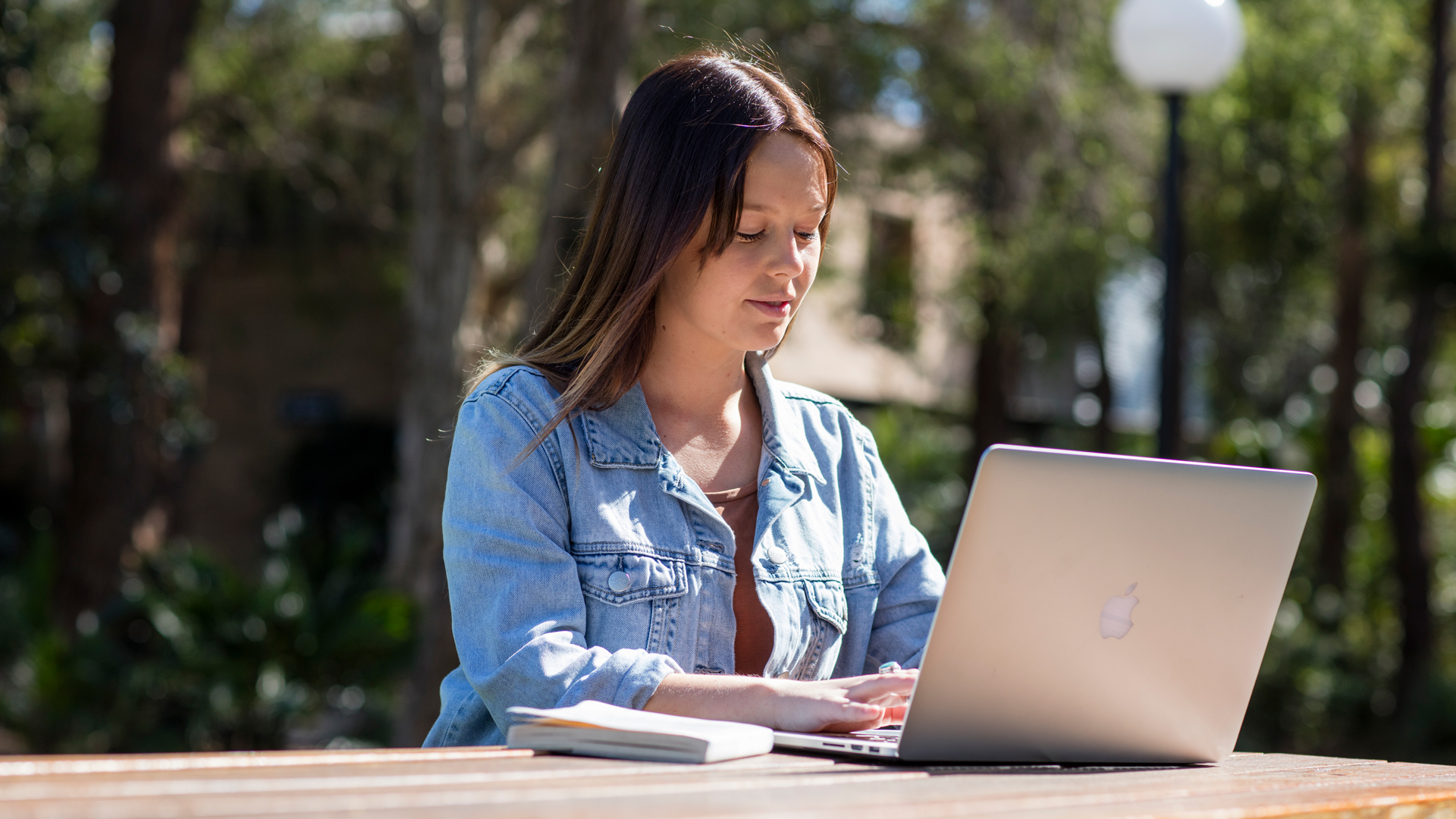 Student typing on a laptop outside