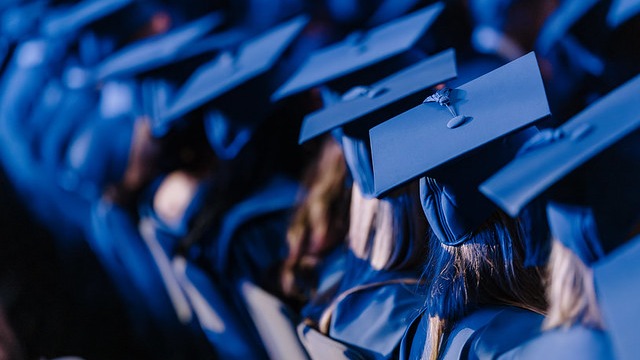 Students sitting with their graduation robes and caps on