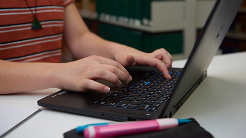 Hands typing on a laptop