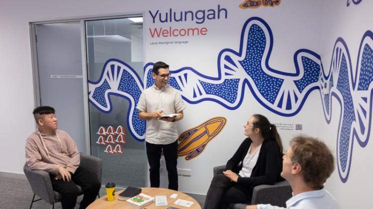 Chaplain stands to talk to three sitting students and staff