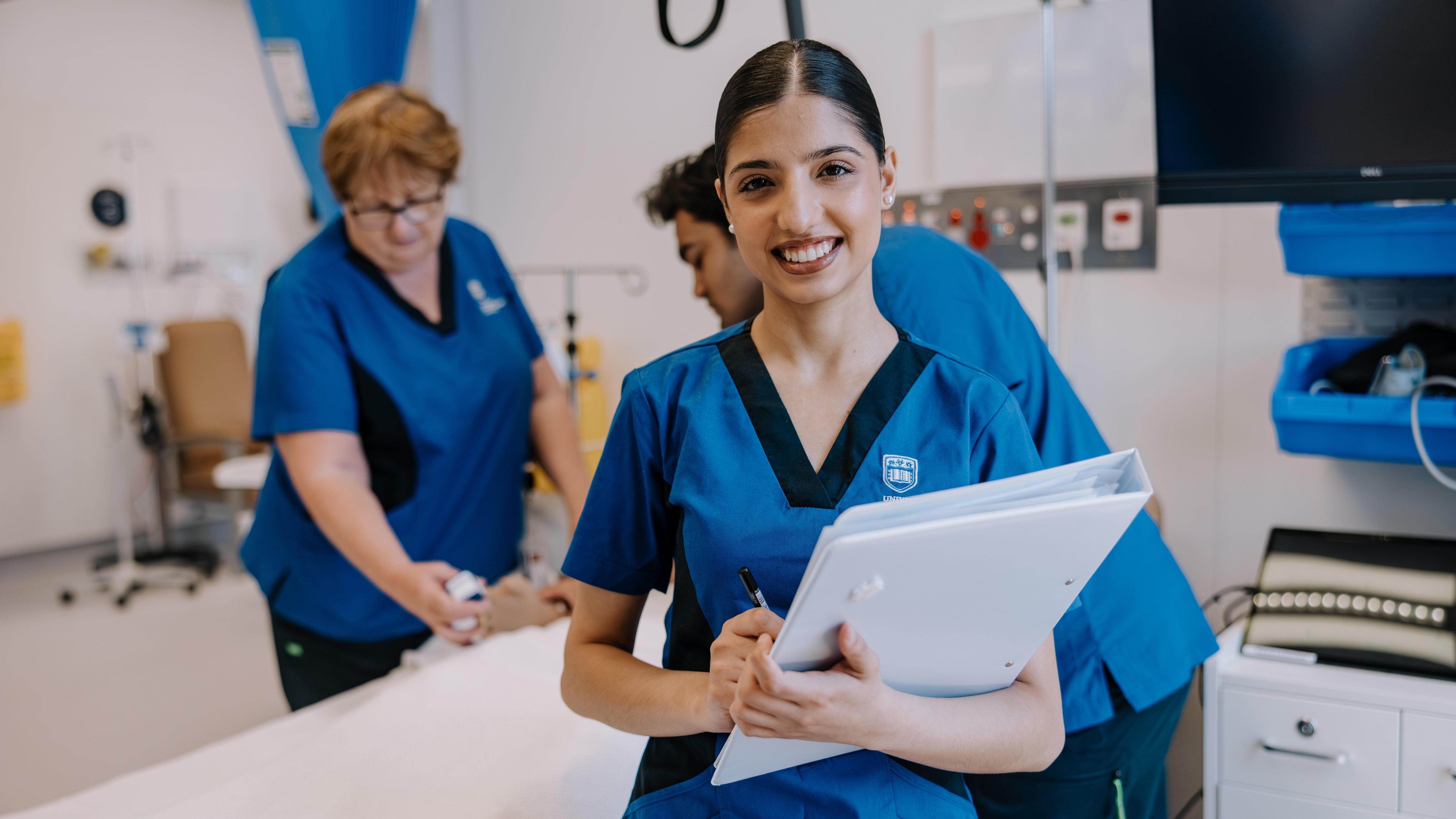 Student nurse holding patient notes in a clinical training ward.