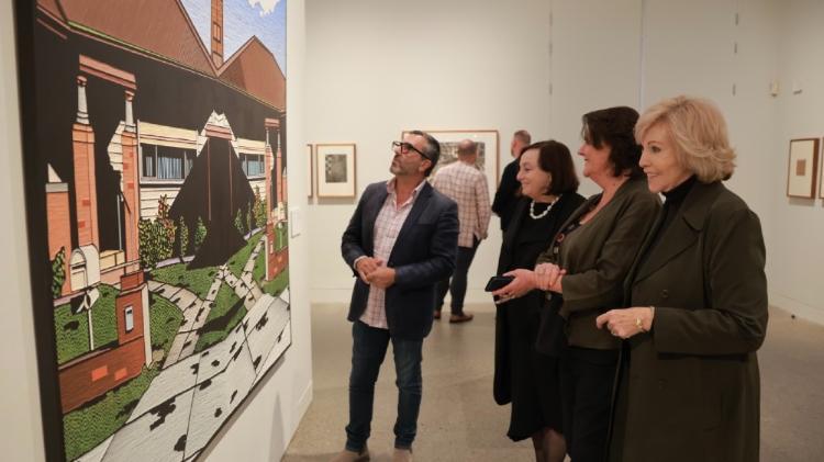 People looking at artwork hanging on a wall