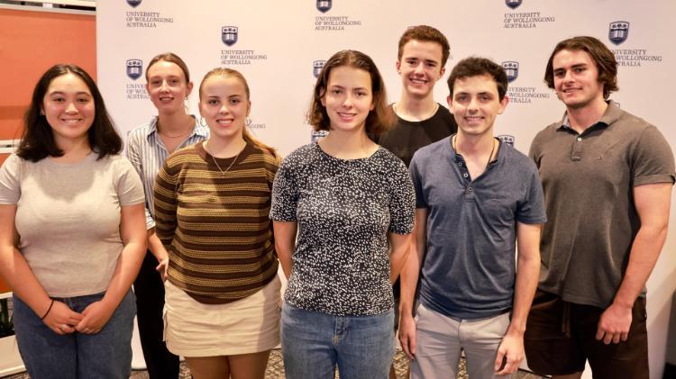 Eight students stand in front of a UOW backdrop at the Westpac Young Scholars event. Photo: Mark Newsham