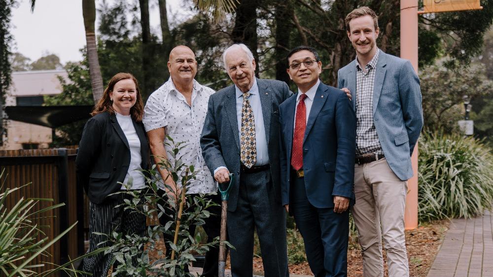 Professor Lisa Kervin, Professor Paul Chandler, Mr Chris Abbott, Professor Max Lu AO, Mr Josef English stand outside smiling at the camera during the planting of a tree to celebrate 10 years of Early Start.