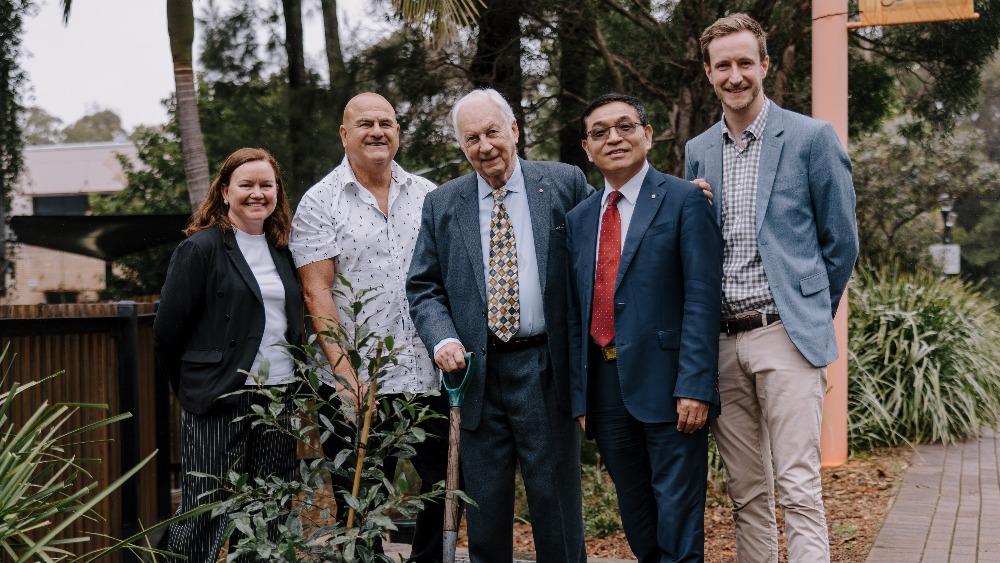 Professor Lisa Kervin, Professor Paul Chandler, Mr Chris Abbott, Professor Max Lu AO, Mr Josef English stand outside smiling at the camera during the planting of a tree to celebrate 10 years of Early Start.