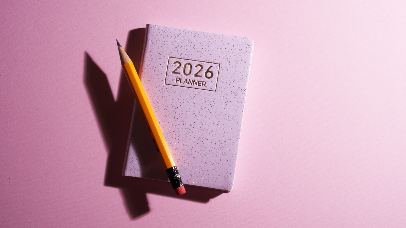 2026 small planner and pen against pink background. Shutterstock 2670066879