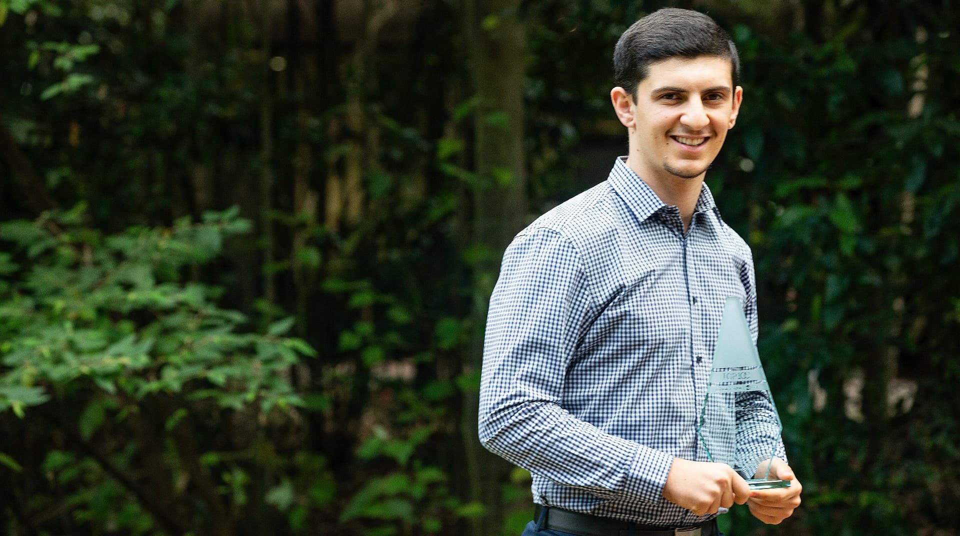 An image of student Adam Karayannis, wearing a blue shirt, among the trees at UOW