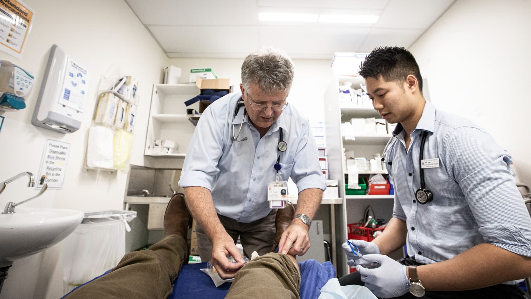 An established GP shows a medical student how to perform a procedure on a patient in a hospital bed. Photo: Paul Jones