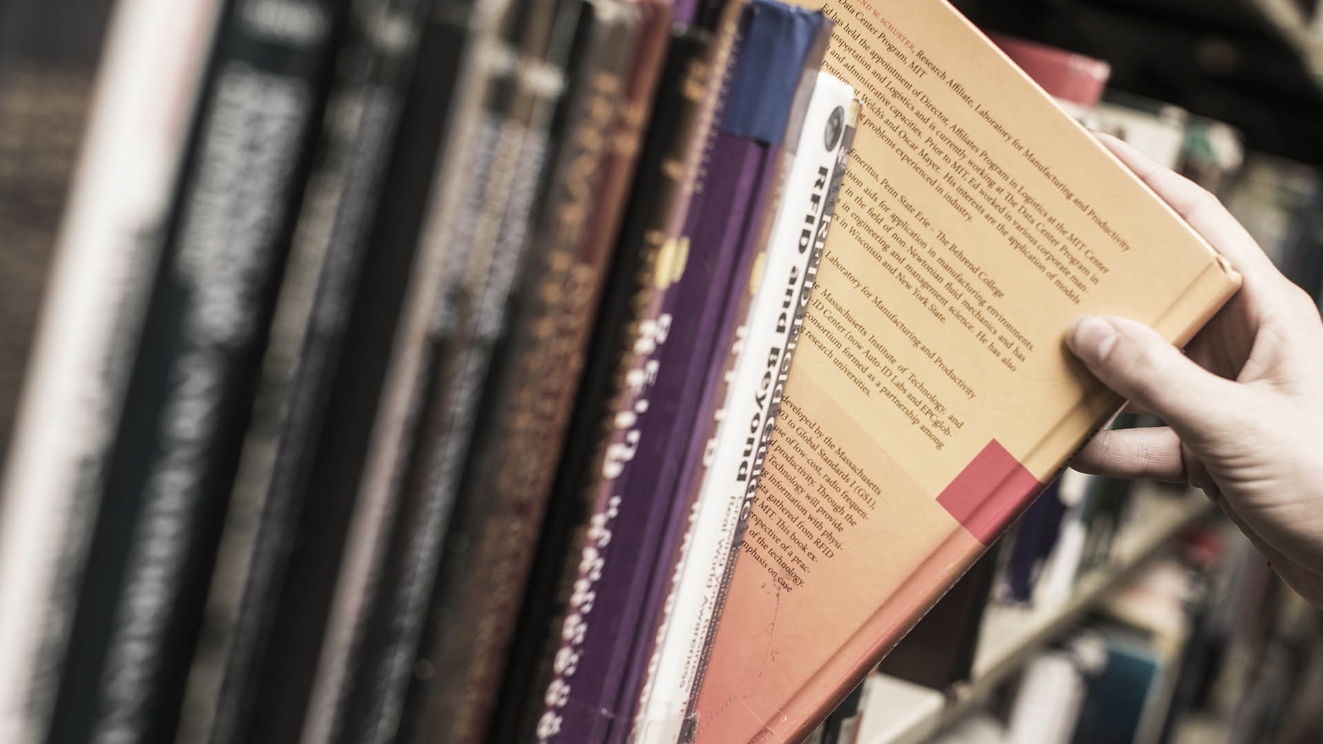 A student takes a book from a bookshelf.
