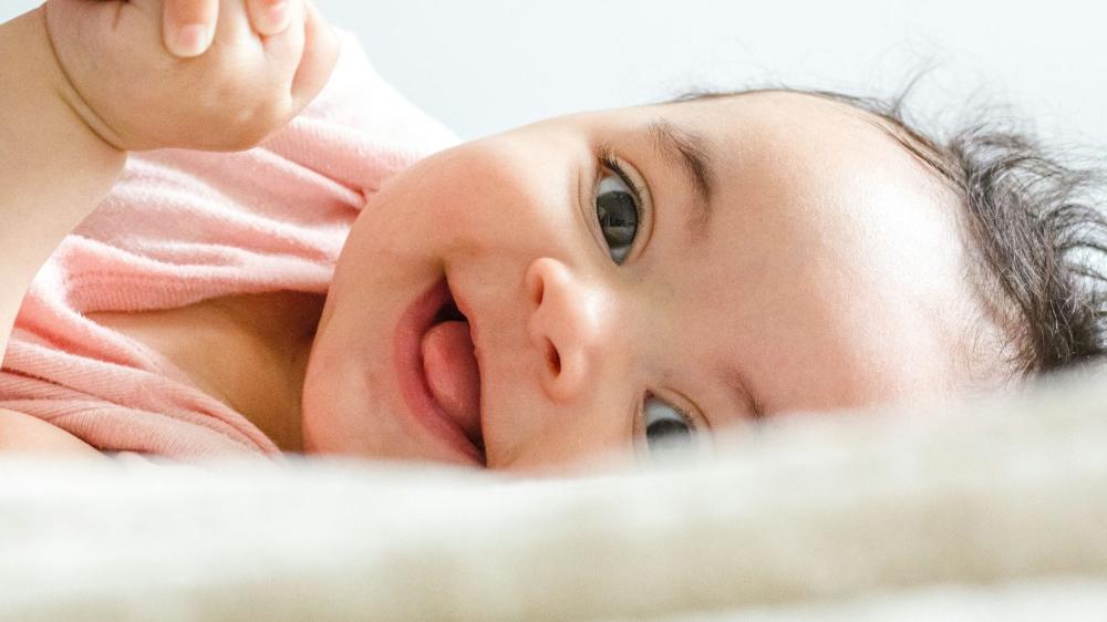A baby lying down and smiling