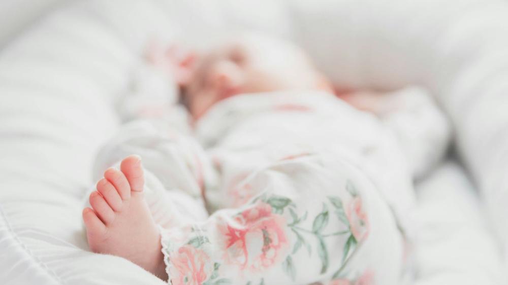 An image of a baby peacefully asleep in a white cot
