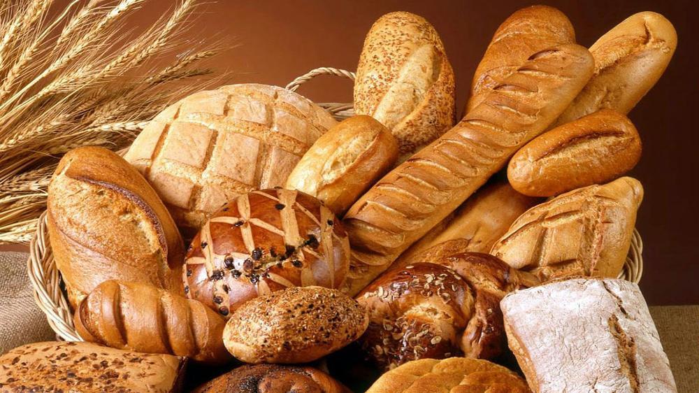 A pile of different bread rolls and loaves of bread all mixed together.