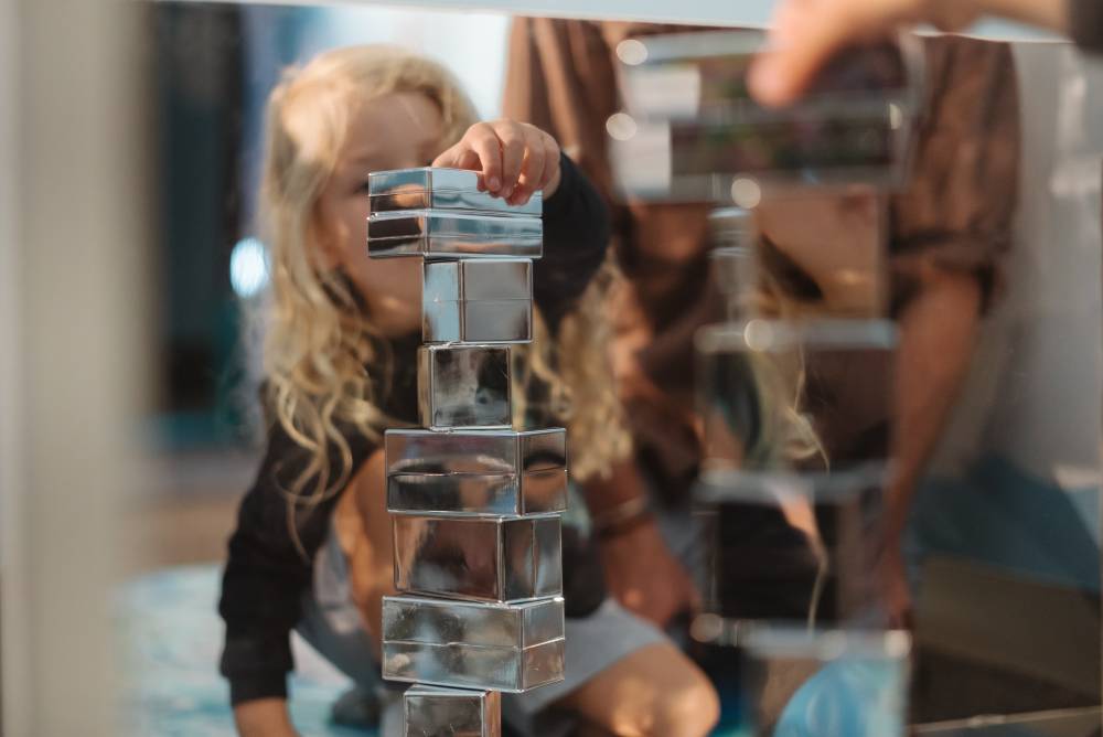 A child at the Discovery Space playing with mirrored blocks in The Sanctuary play experience.