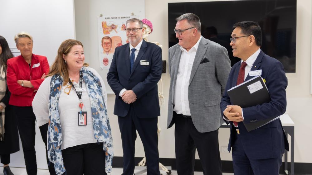 A group of people stand smiling during a tour of medical facilities at UOW Southern Highlands. Photo: Mark Newsham