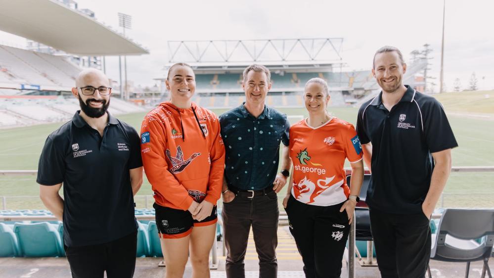 From left, Ryan Anthony (PhD candidate), Tara McGrath, Dr Greg Peoples, Nicola Jaffrey, and Dr Mike Macartney in the stands of WIN Stadium with the field in the background. Photo: Michael Gray