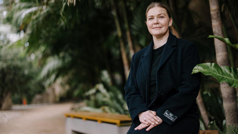 Early childhood educator Ashleigh Ceeney sits on a bench against a background of bushes. Photo: Michael Gray