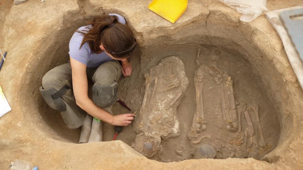 A woman digs in a pit, with skeletons in ground, in the ancient city of Catalhoyuk. Photo: Eline Schotsmans