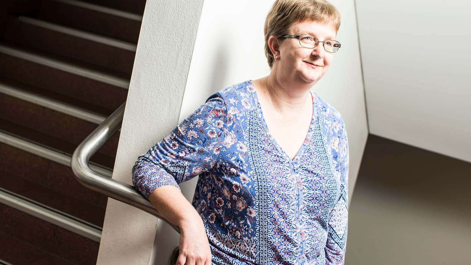 A woman leans against the rail of a stairwell. Photo: Paul Jones
