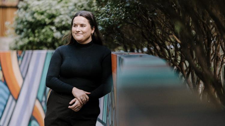 Early childhood educator Emma Stevenson, wearing a black top, leans against a wall outside Early Start. Photo: Michael Gray