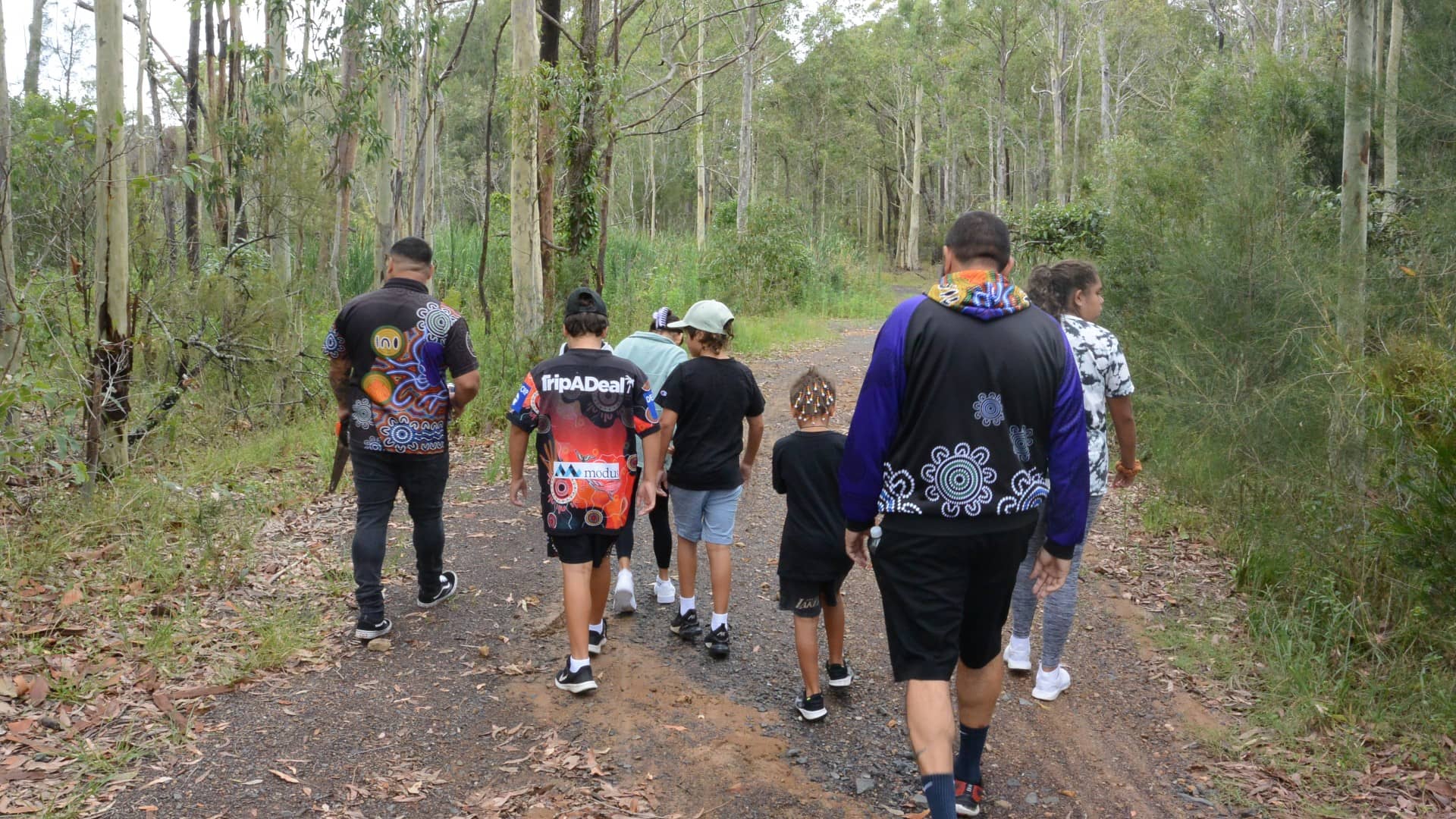 A group of students with mentors from the Koori Kids Culture Club are seen walking into the bush. Photo: Supplied