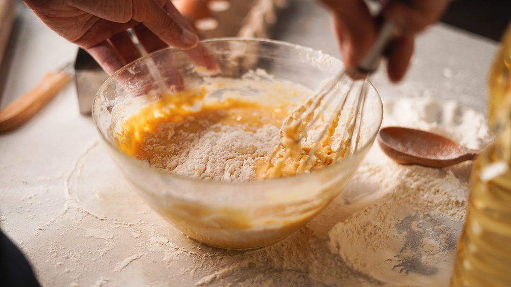 A close-up of a cooking mixing batter in a bowl.