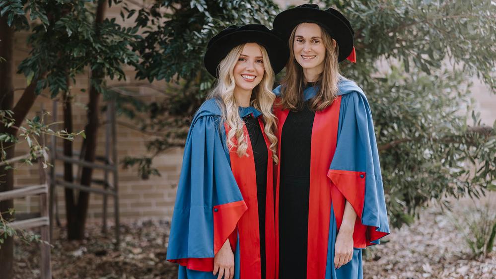 Emma James and Danielle Warren in academic dress to celebrate their graduation.