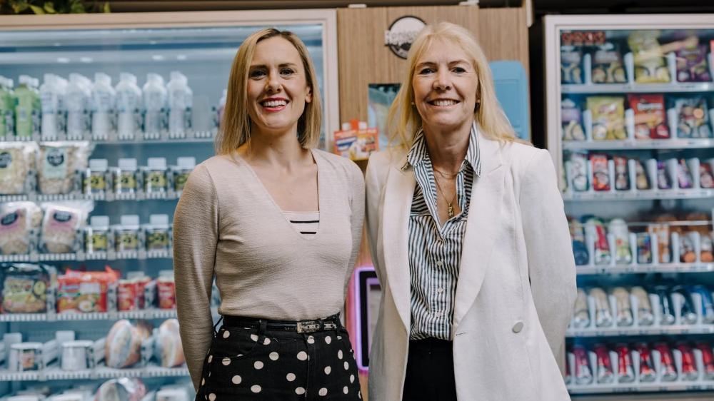 Katherine Kent and Karen Charlton stand in front of two vending machines. Photo: Michael Gray