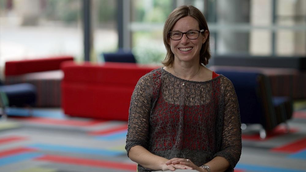 A/Professor Jenny Fisher sitting on a sofa smiling